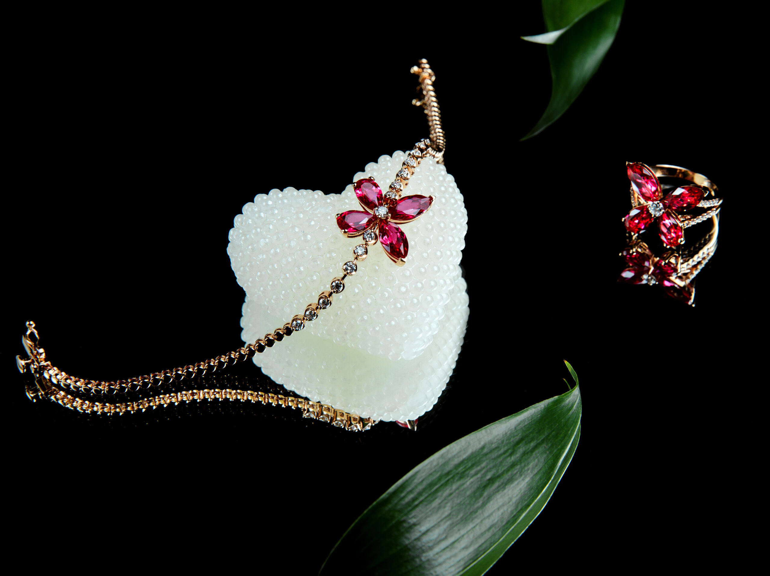 side view of jewellery set of golden bracelet and rind with diamonds and rubies in a shape of butterfly